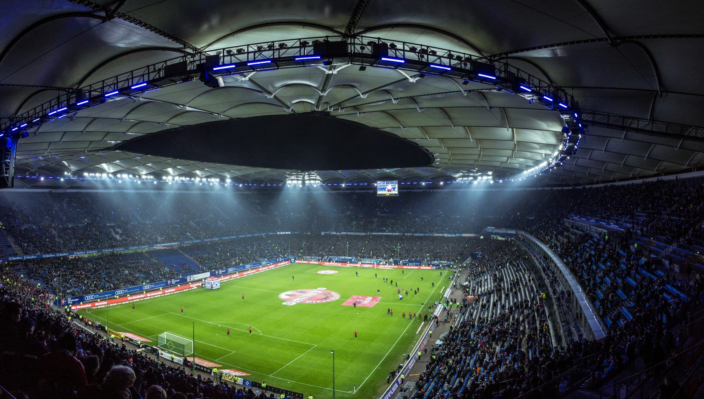 Flutlichtmasten einer Arena leuchten in die Nacht